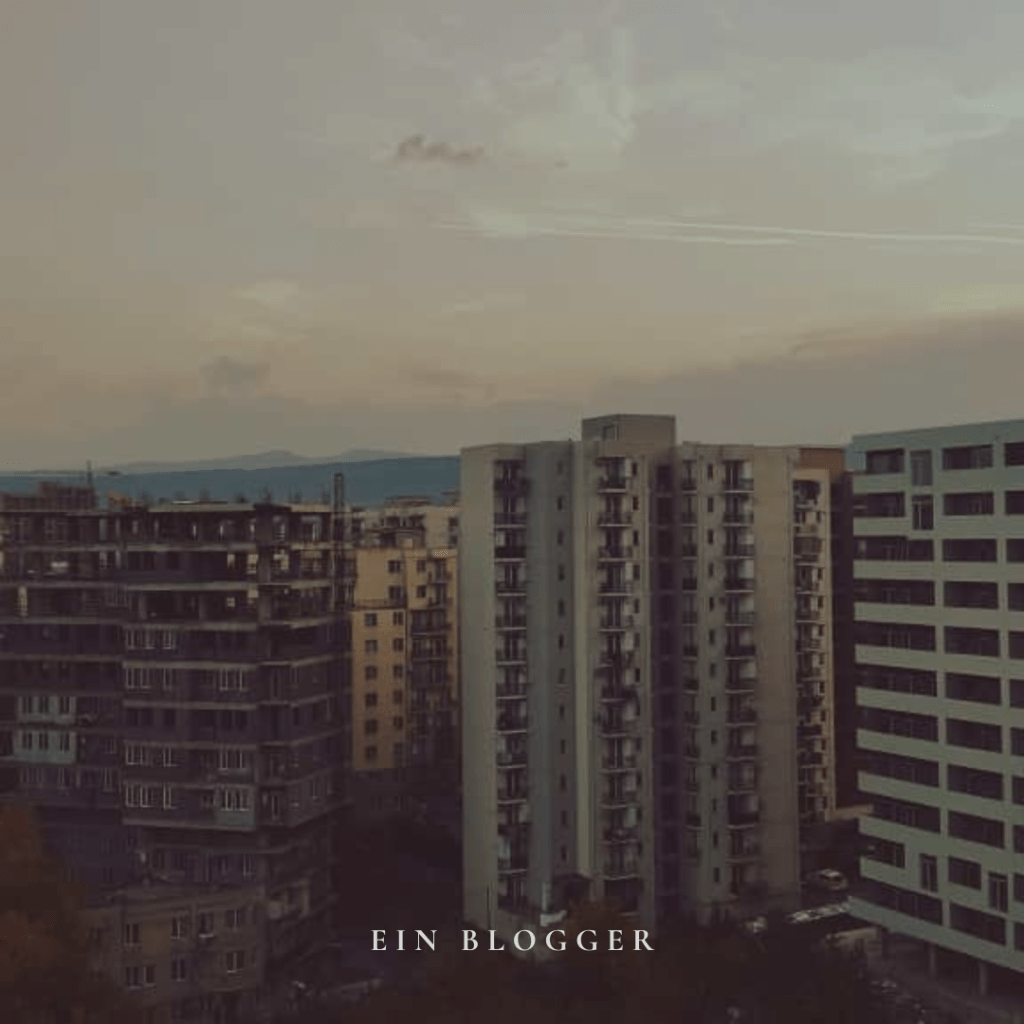 Blick auf mehrere Hochhäuser in Tiflis, mit einem verschiedenen architektonischen Stil und einem sanften Abendhimmel im Hintergrund.